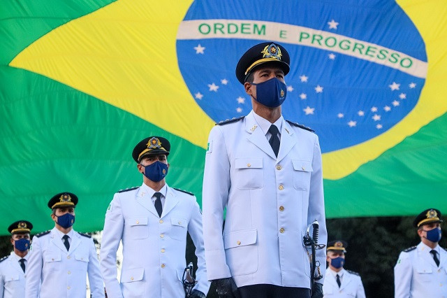 Oficiais da PM DF perto da bandeira do Brasil