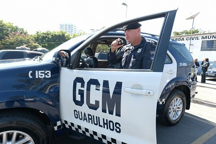 Guarda municipal de Guarulhos em frente a uma viatura 